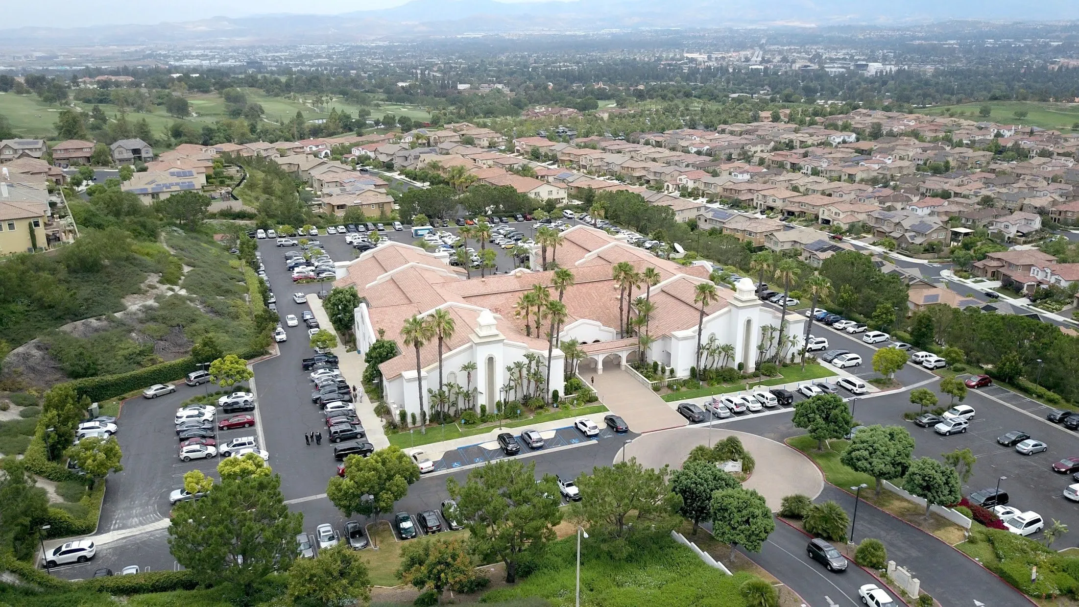 High aerial view of the Aliso Viejo Community Center in California, showing mission-style buildings, parking lots, and nearby home.