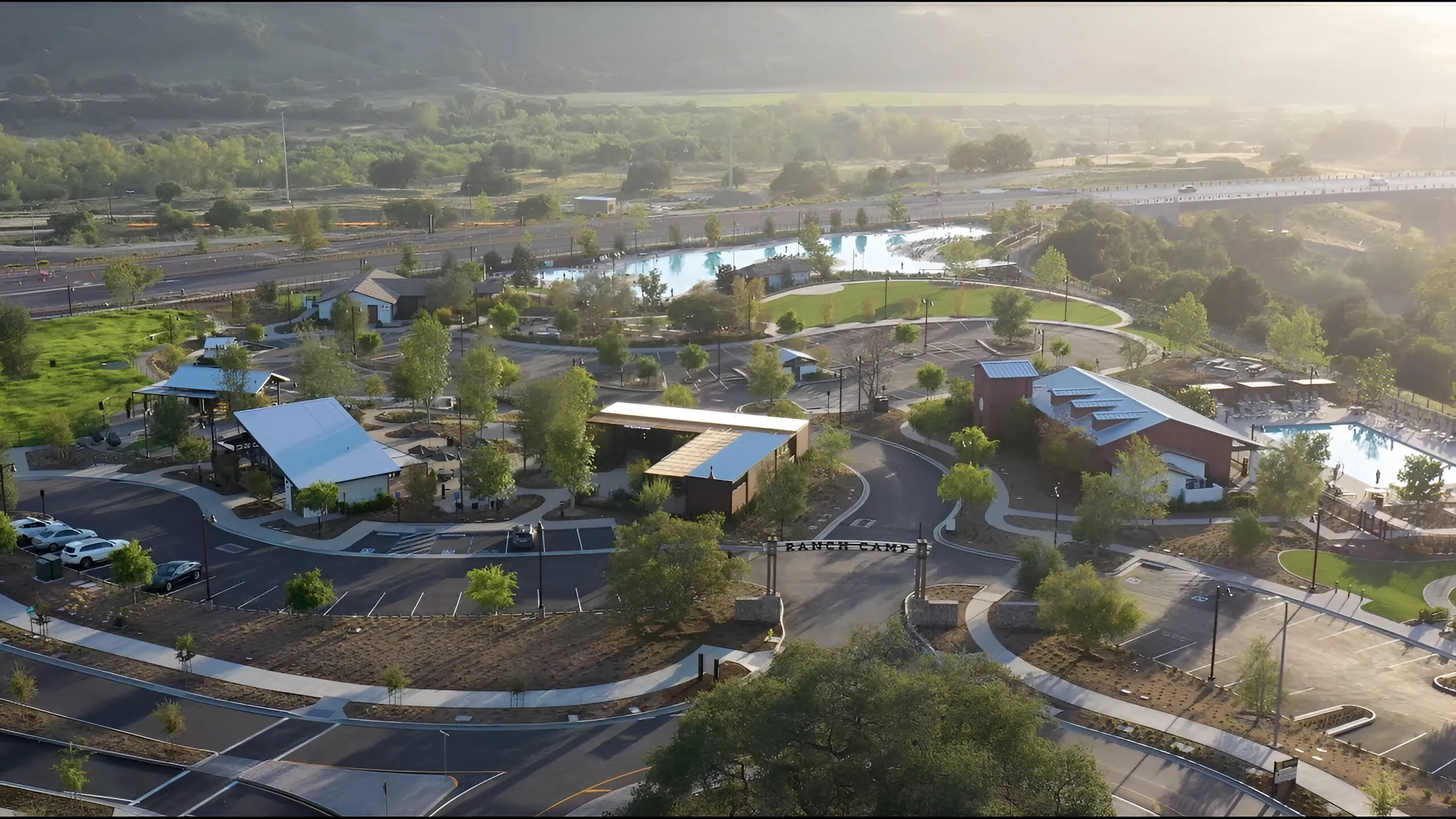 Aerial view of Ranch Camp at Rancho Mission Viejo, California, showing pools, modern buildings, and rolling hills.