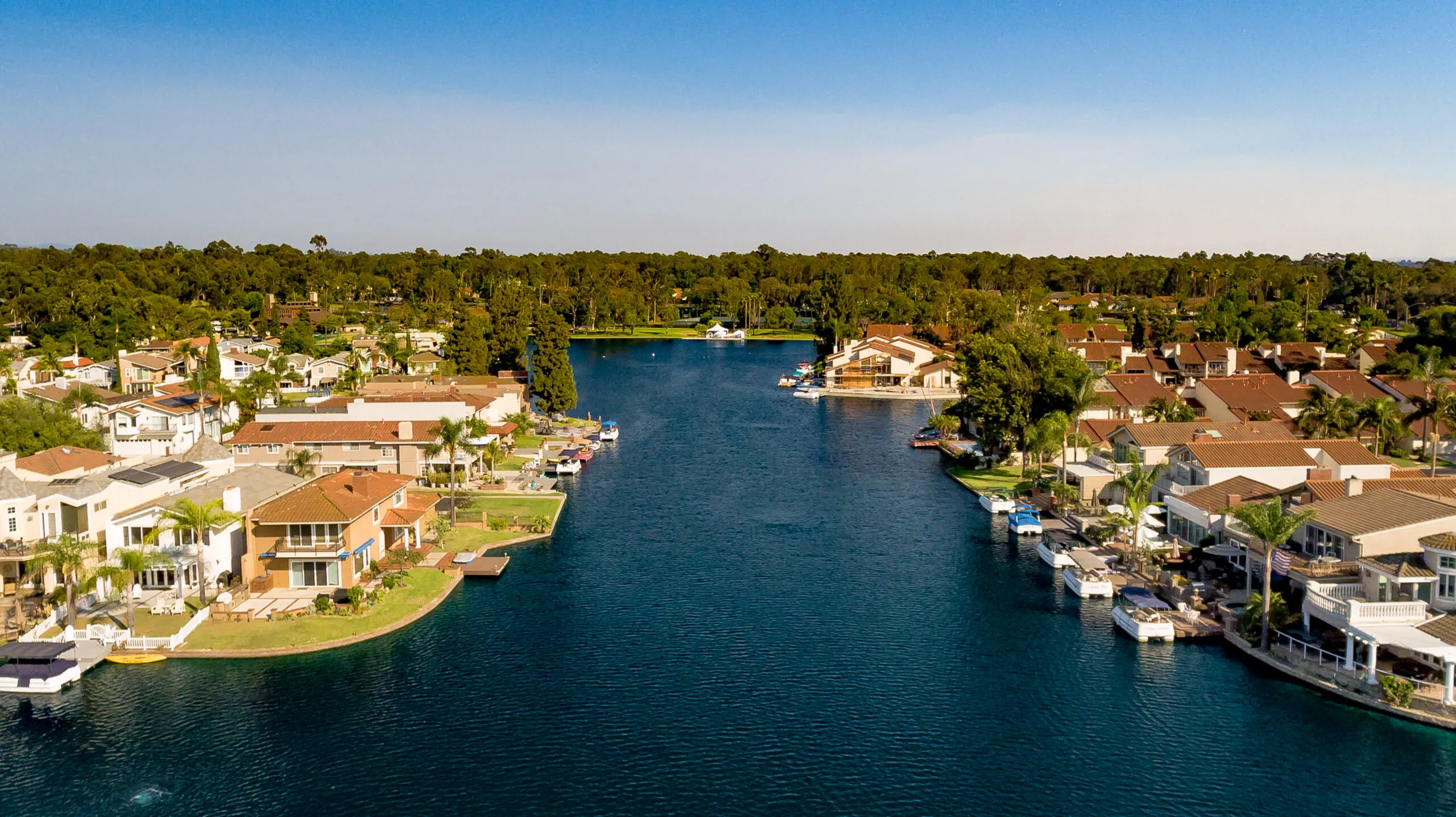 Aerial view of Lake Forest, California homes along North Lake with private docks, boats, and trees around the neighborhood.