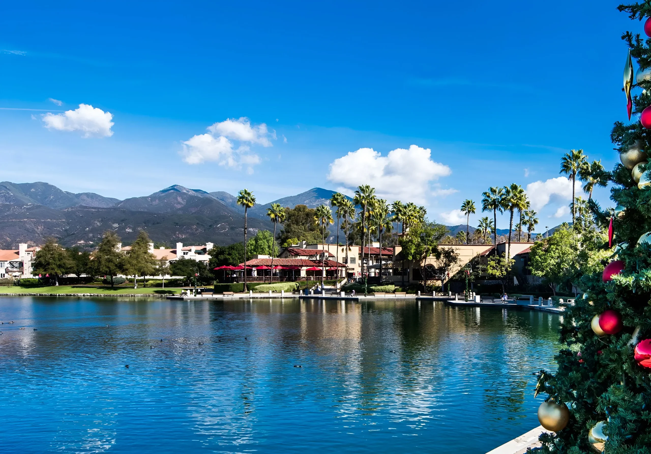 Scenic view of Santa Margarita in Rancho Santa Margarita, California, with a holiday tree and the Saddleback Mountains reflected in the lake at sunset.