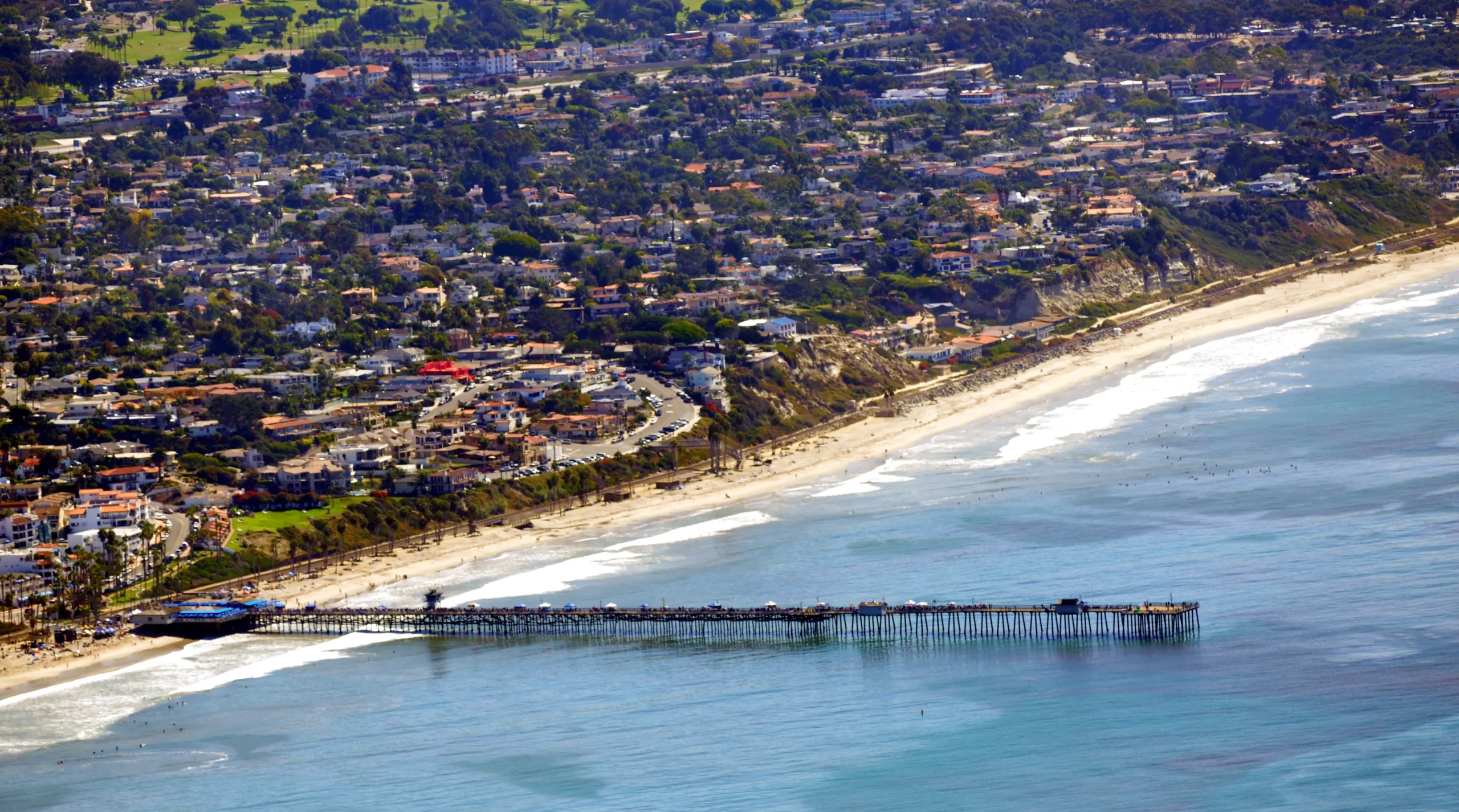 Aerial view of San Clemente, California, showing the pier, beachfront homes, and the coastal community.